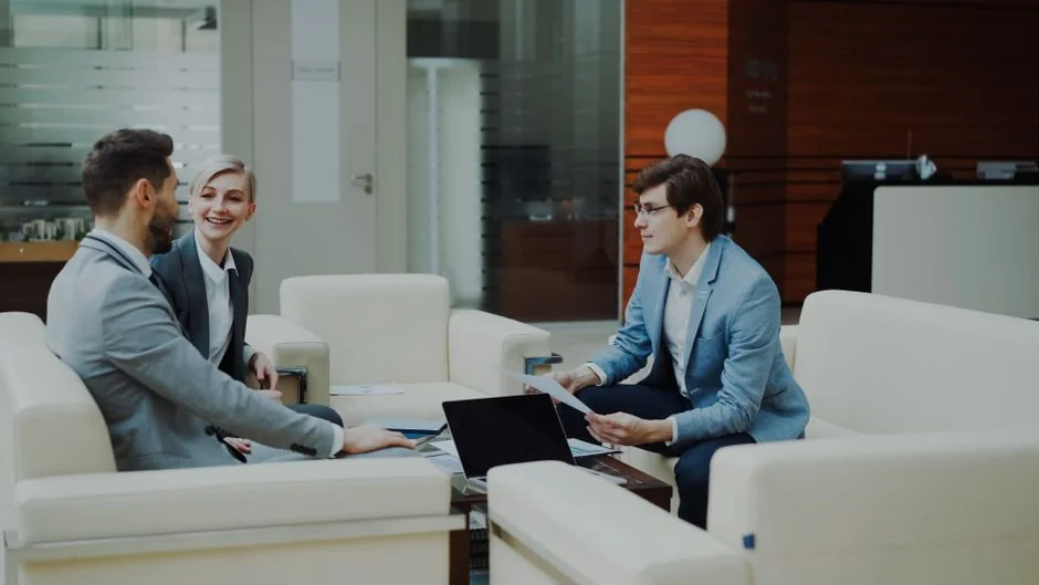 Person analyzes stock data with a smartphone and laptop, indoors.