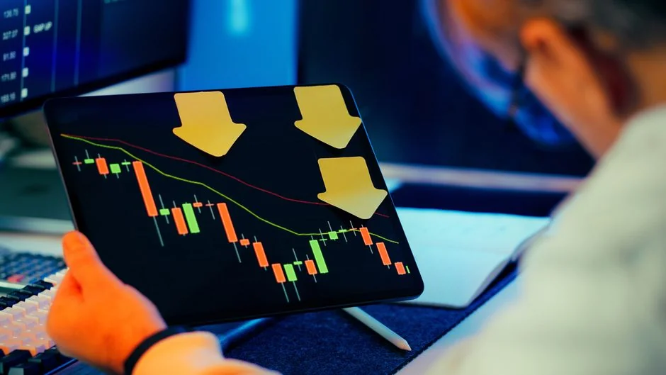 Des mains tapant sur un ordinateur portable, avec des graphiques de cryptomonnaies et l’écran d’un smartphone visibles, centrés sur la finance numérique.